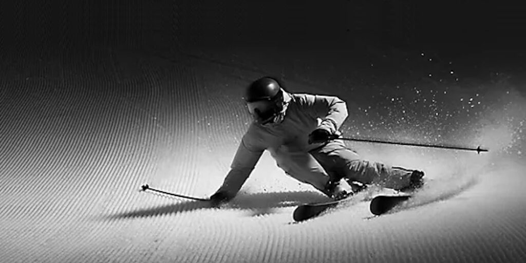 Schwarz-Weiss-Bild eines Skifahrers auf planiertem Schnee