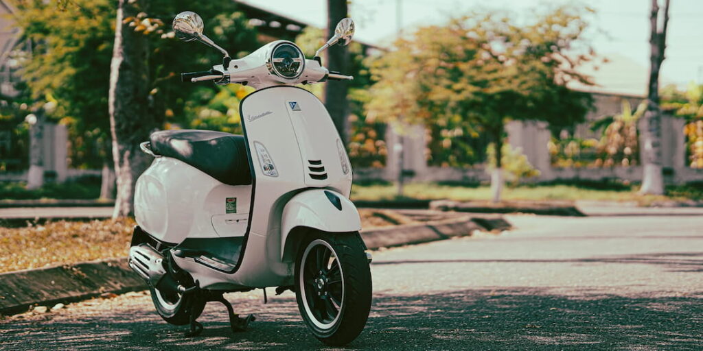 Weisse Vespa auf der Strasse stehend