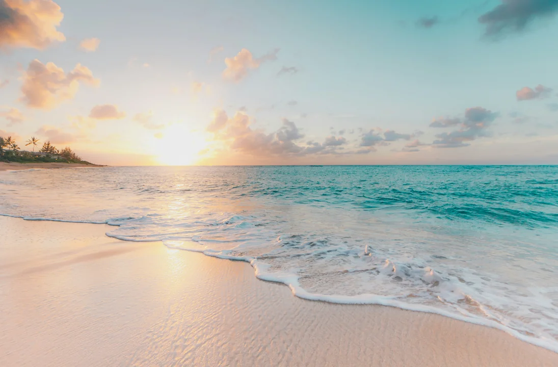 Sonnenuntergang über türkisfarbenem Meer mit weissem Sandstrand